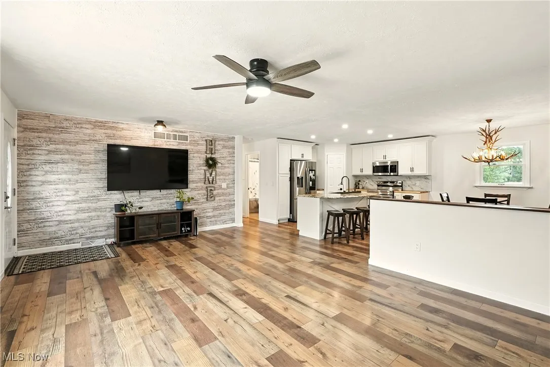 Living room with light wood-style flooring, a chandelier, and ceiling fan