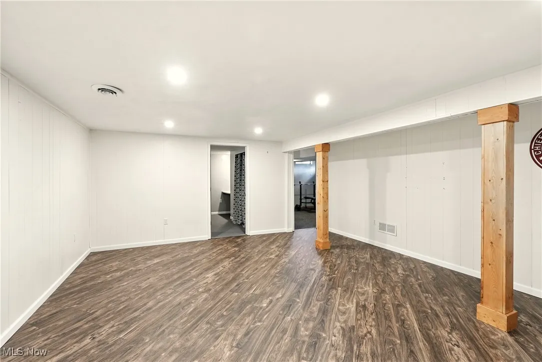 Finished below grade area with dark wood-style flooring, wood walls, and recessed lighting