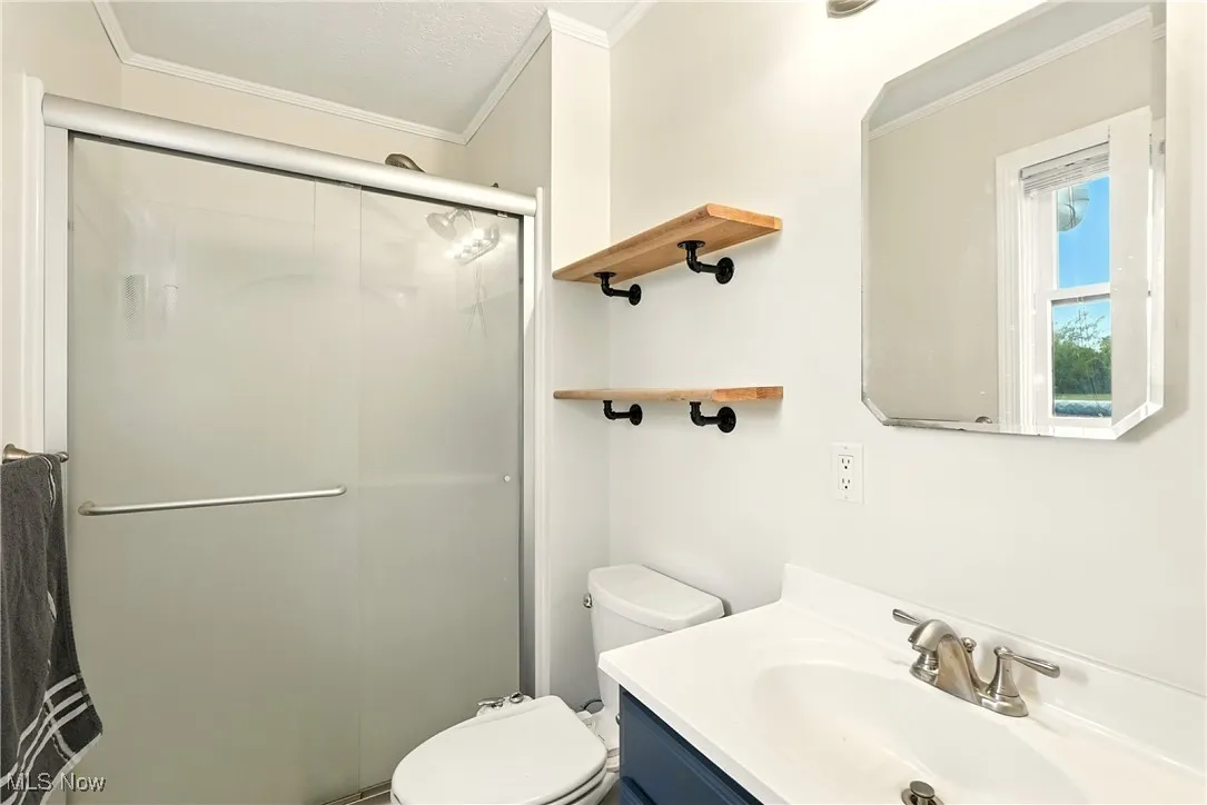Full bath featuring vanity, a shower stall, and crown molding
