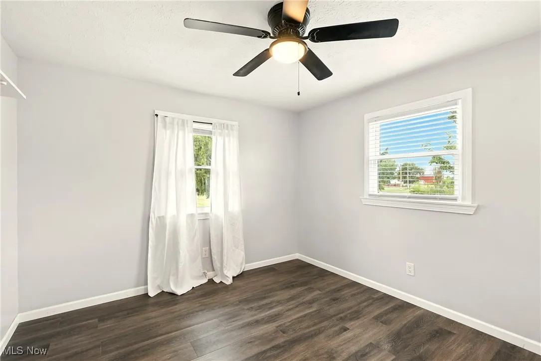 Unfurnished room featuring dark wood-style floors, a textured ceiling, and a ceiling fan