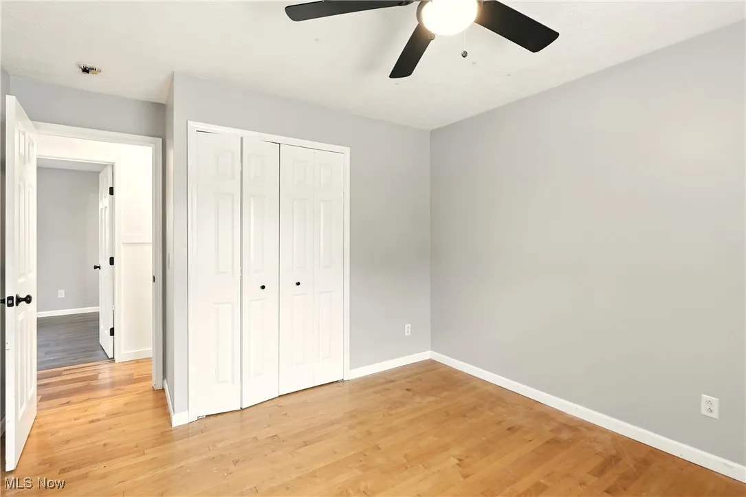 Unfurnished bedroom with light wood-style floors, a closet, and a ceiling fan