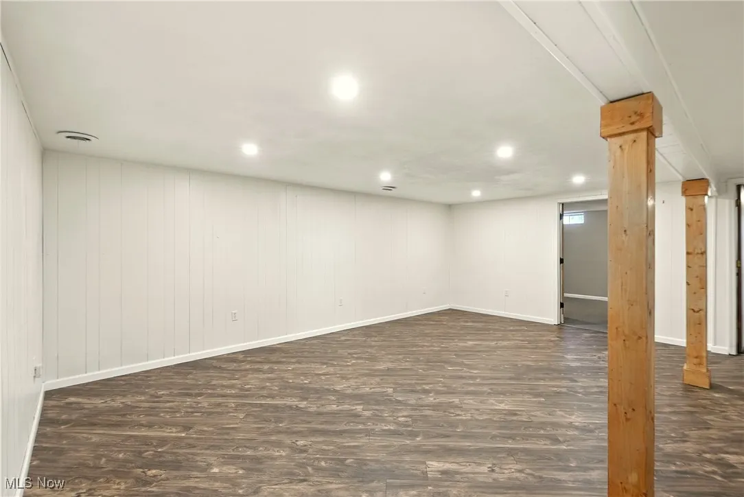 Finished below grade area featuring dark wood-style floors, recessed lighting, and wood walls