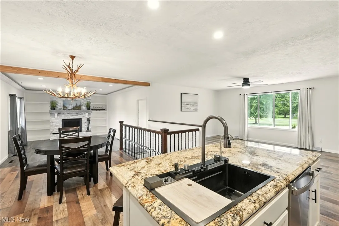 Kitchen with open floor plan, dark wood-type flooring, light stone countertops, beam ceiling, and a textured ceiling