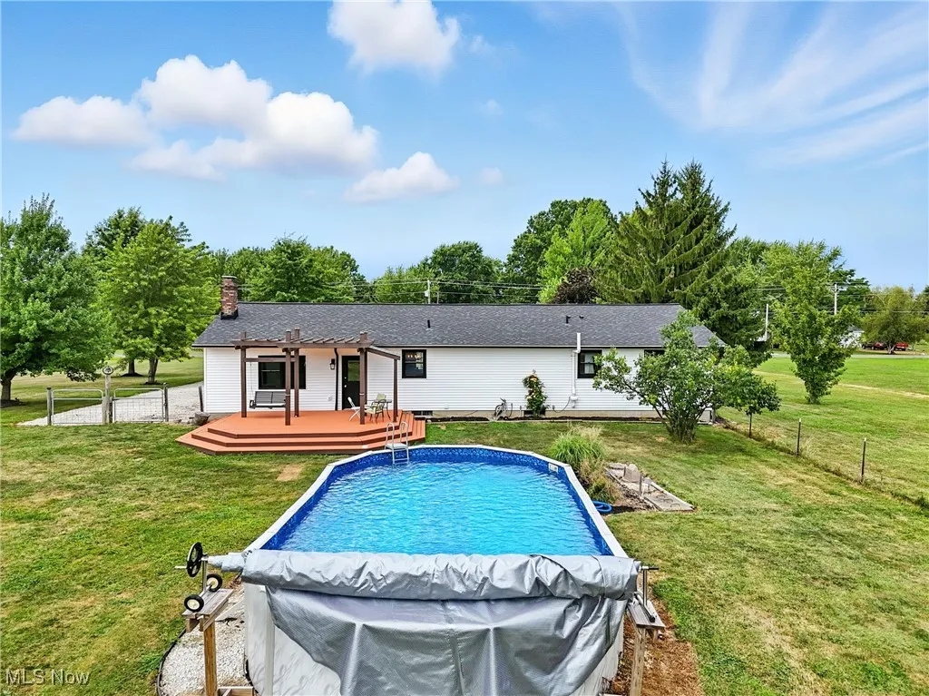 Swimming pool featuring a fenced backyard, a wooden deck, and a patio area