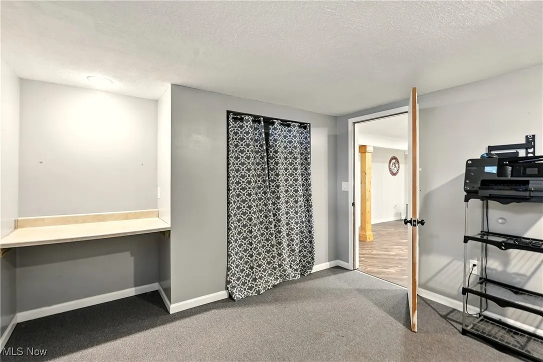 Unfurnished office featuring a textured ceiling, carpet, and built in desk