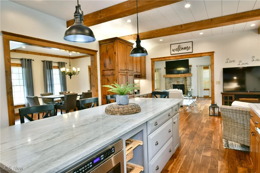 Kitchen with recessed lighting, a fireplace, light stone countertops, decorative light fixtures, and dark wood finished floors