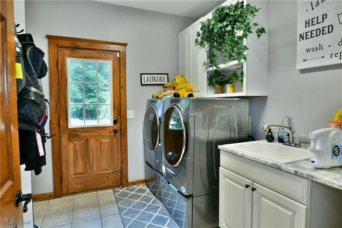 Laundry area with cabinet space, washing machine and clothes dryer, and light tile patterned floors