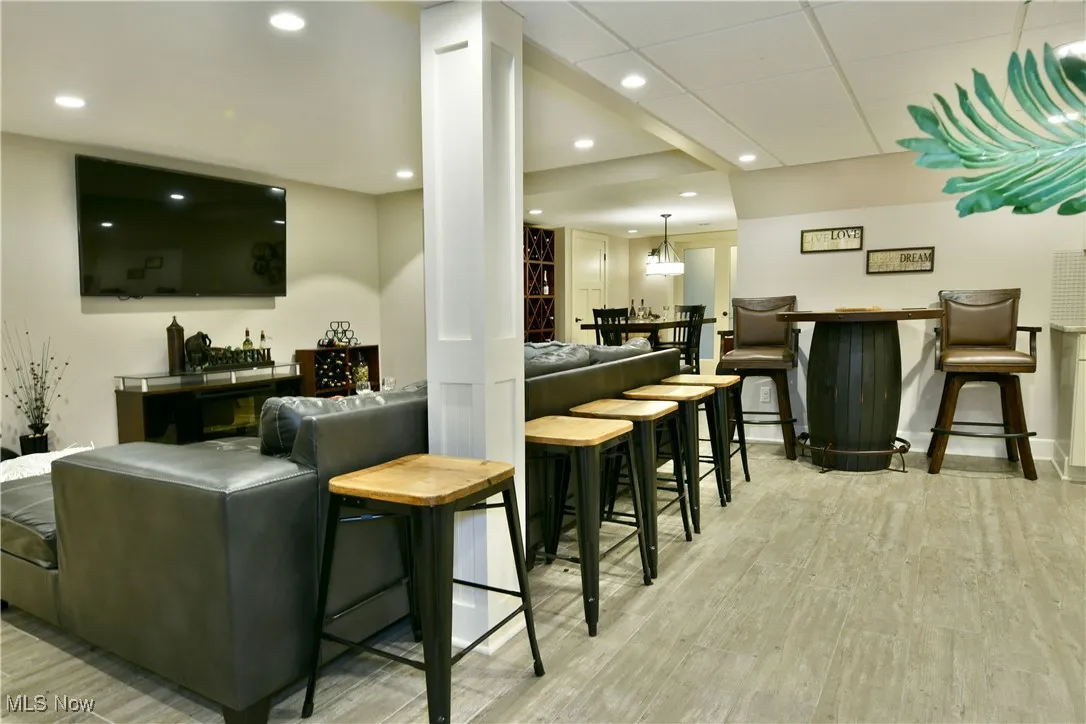 Bar featuring light wood finished floors, recessed lighting, decorative light fixtures, and a paneled ceiling
