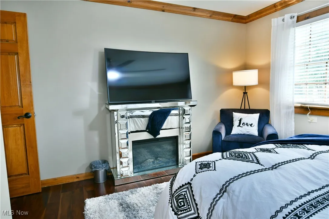 Bedroom with wood finished floors and a glass covered fireplace