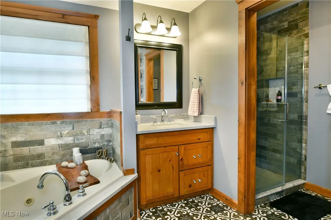 Full bath with vanity, a shower stall, a tub with jets, and light tile patterned flooring