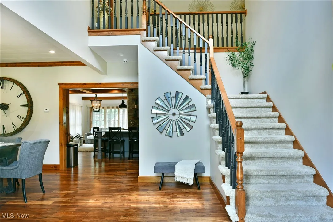 Stairway featuring wood finished floors, recessed lighting, and a high ceiling