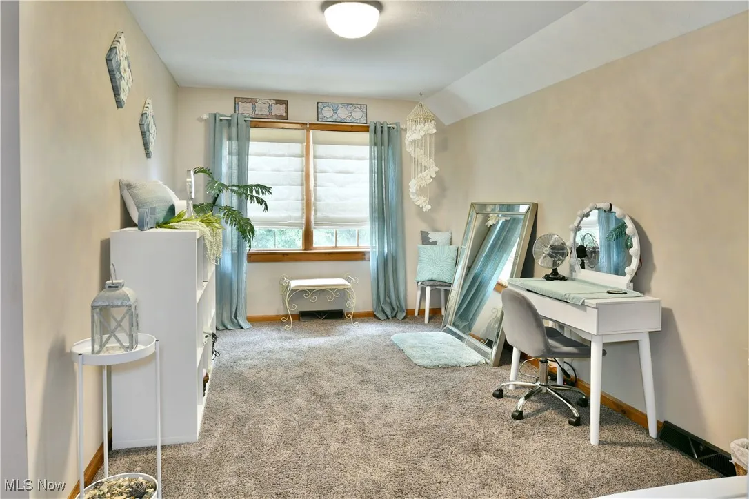 Carpeted office space featuring baseboards and vaulted ceiling