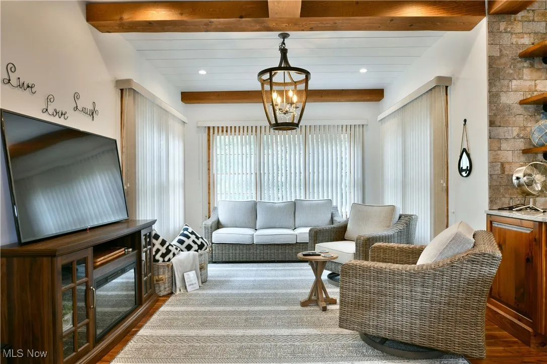 Sitting room featuring dark wood-style floors, beam ceiling, and a chandelier