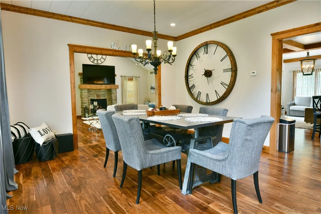 Dining space featuring a chandelier, dark wood-style flooring, a brick fireplace, ornamental molding, and recessed lighting