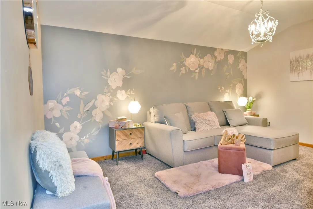 Living area with carpet floors, a chandelier, and vaulted ceiling