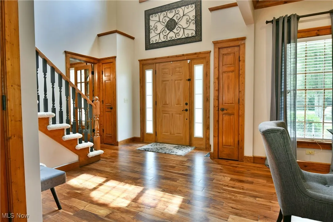 Entryway with stairway, light wood finished floors, plenty of natural light, and a high ceiling