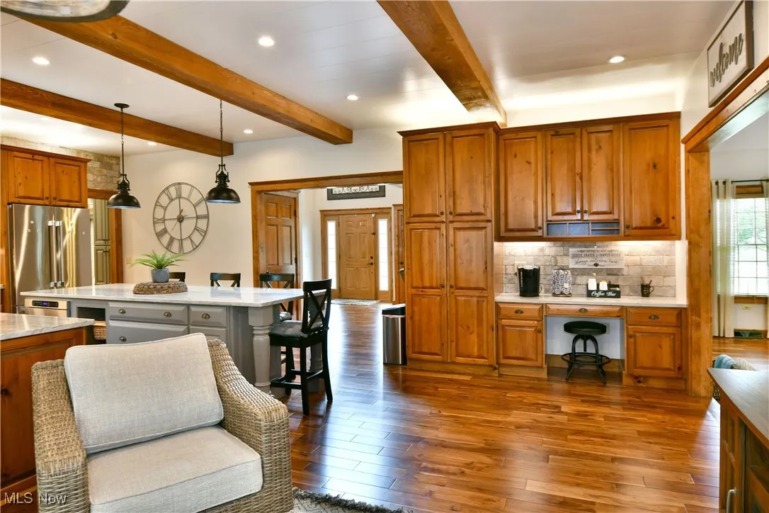 Kitchen with brown cabinetry, recessed lighting, hanging light fixtures, tasteful backsplash, and light stone counters