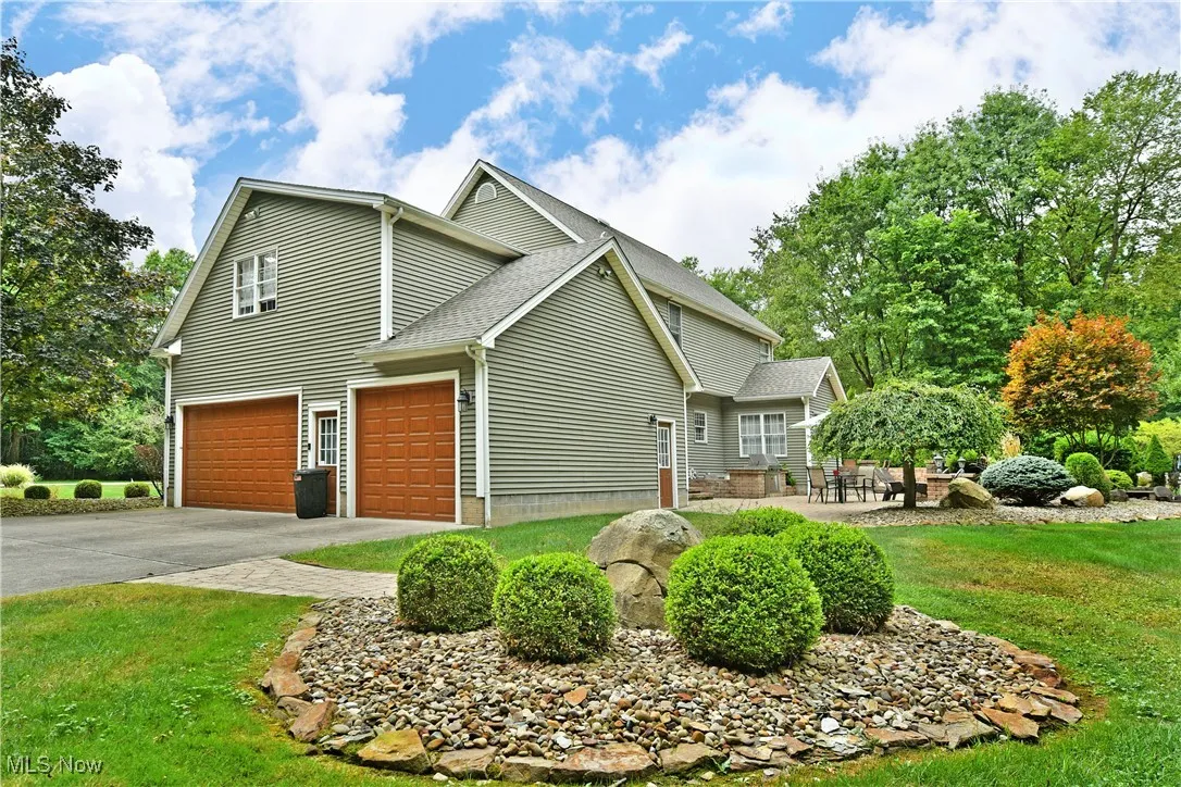View of property exterior featuring a lawn, driveway, roof with shingles, and an attached garage