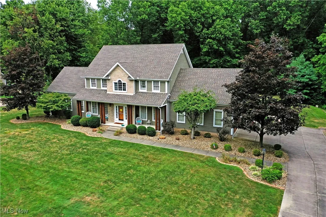 Colonial-style house with covered porch, a shingled roof, and a front yard