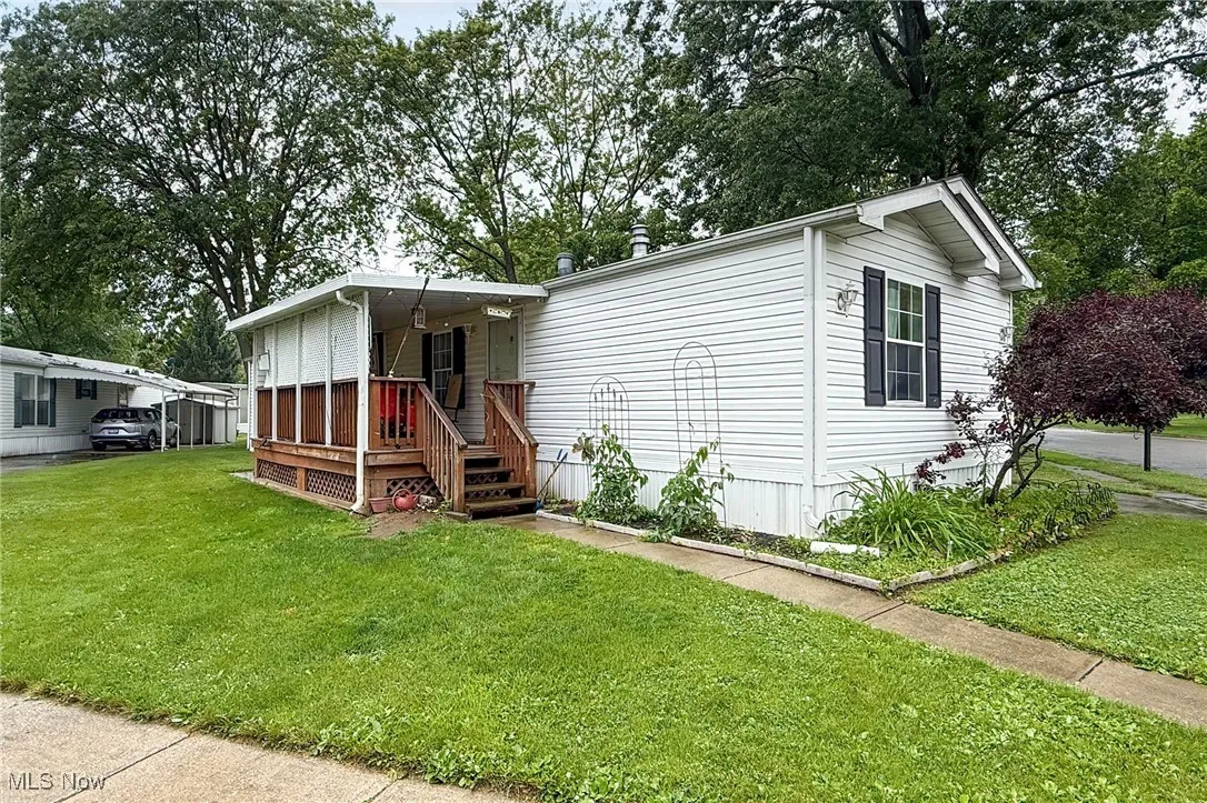 Manufactured / mobile home with a front yard and a carport
