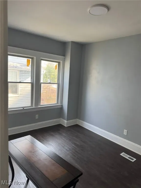 Unfurnished room with dark wood-style flooring and baseboards
