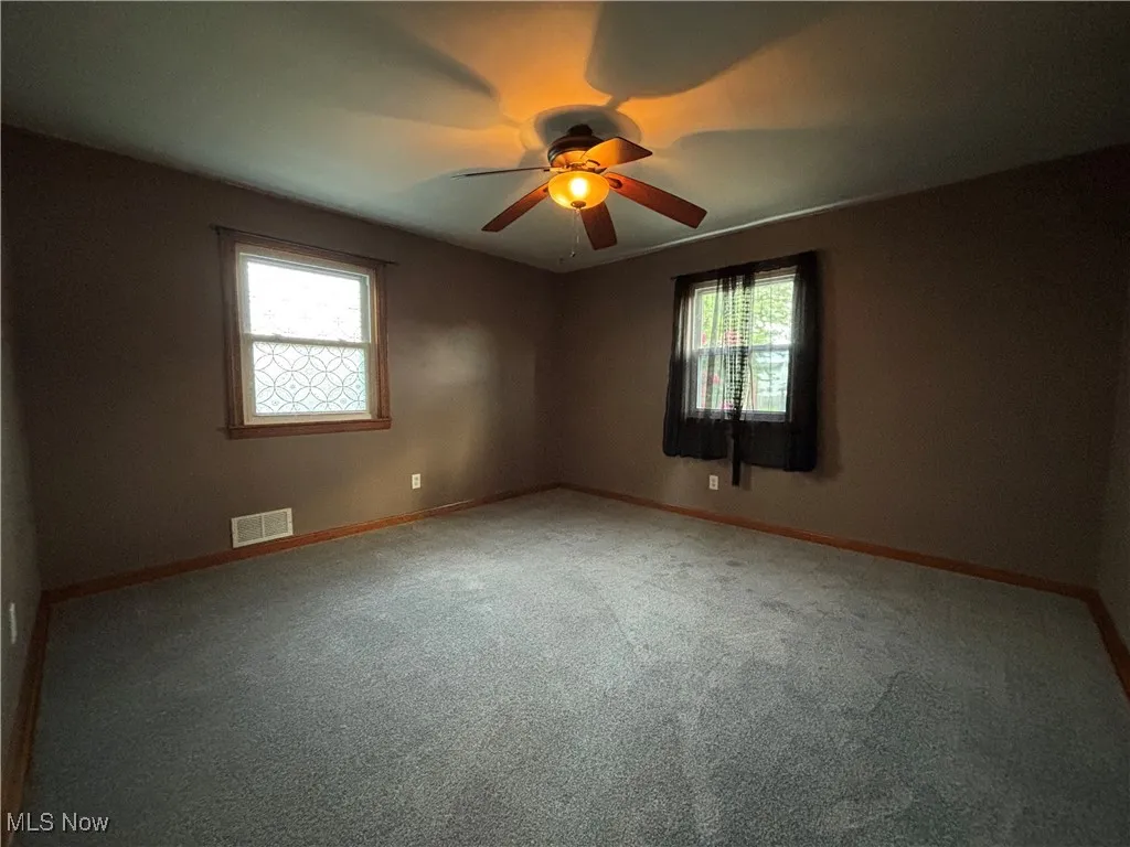 Carpeted spare room with baseboards and ceiling fan