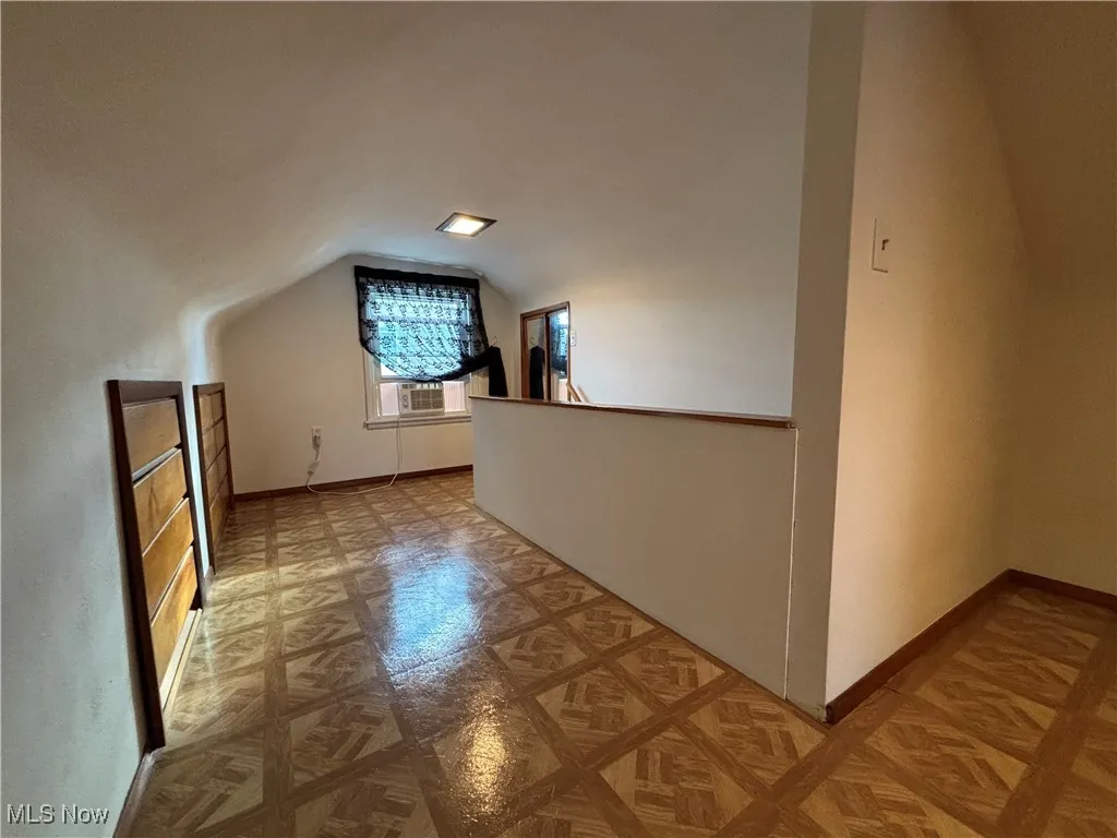 Additional living space with vaulted ceiling and baseboards