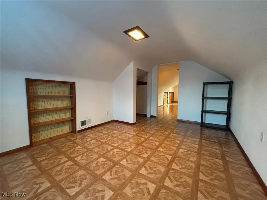 Bonus room with baseboards and vaulted ceiling