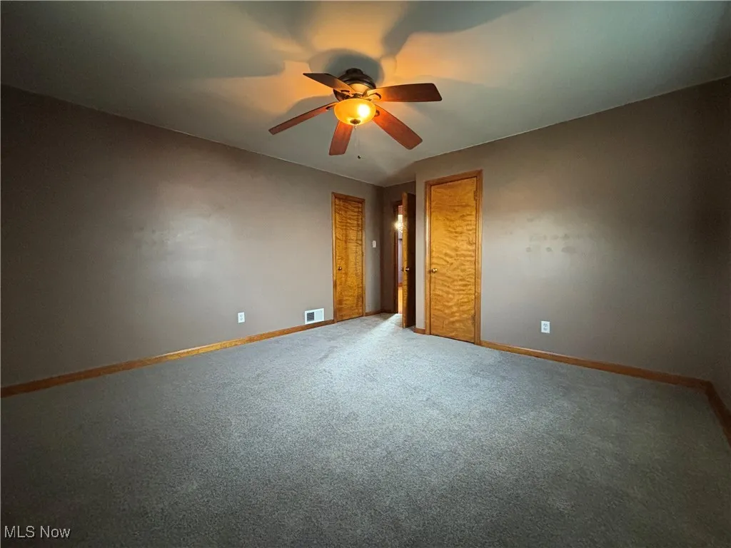 Unfurnished bedroom with ceiling fan and carpet flooring