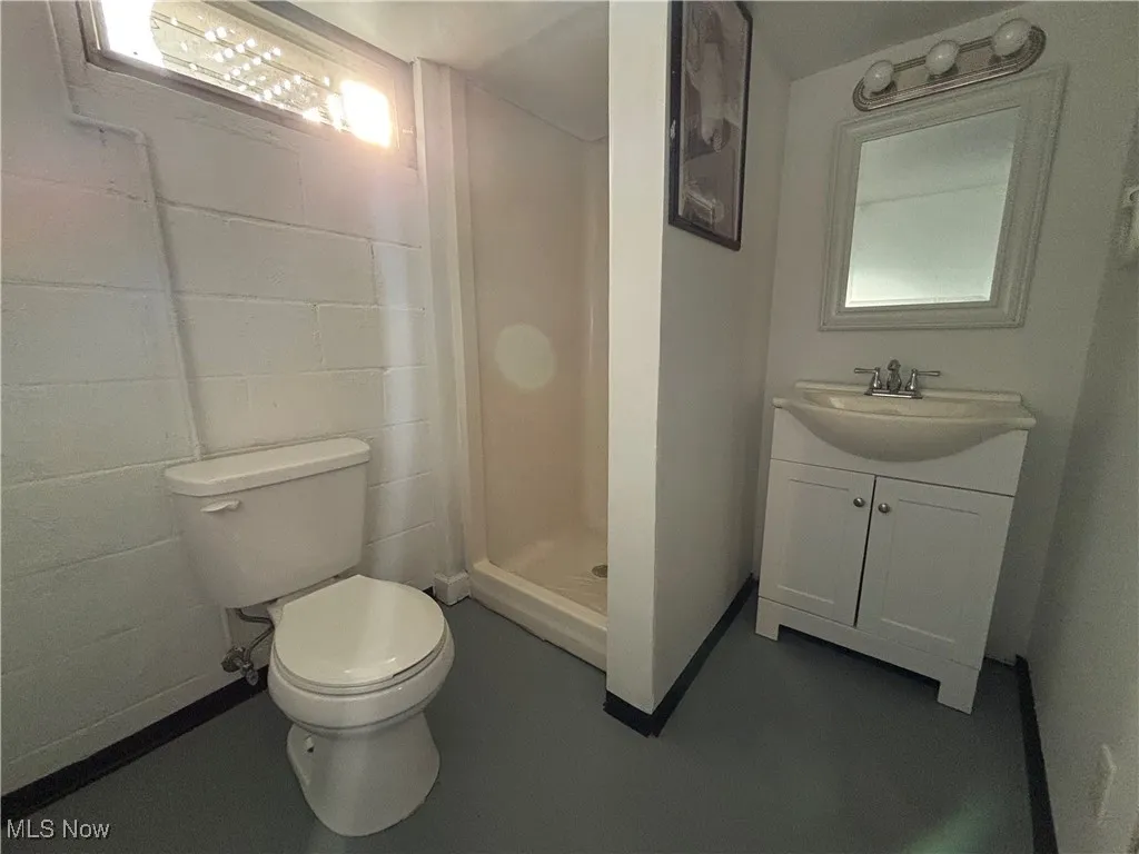 Bathroom featuring a stall shower, vanity, and concrete flooring