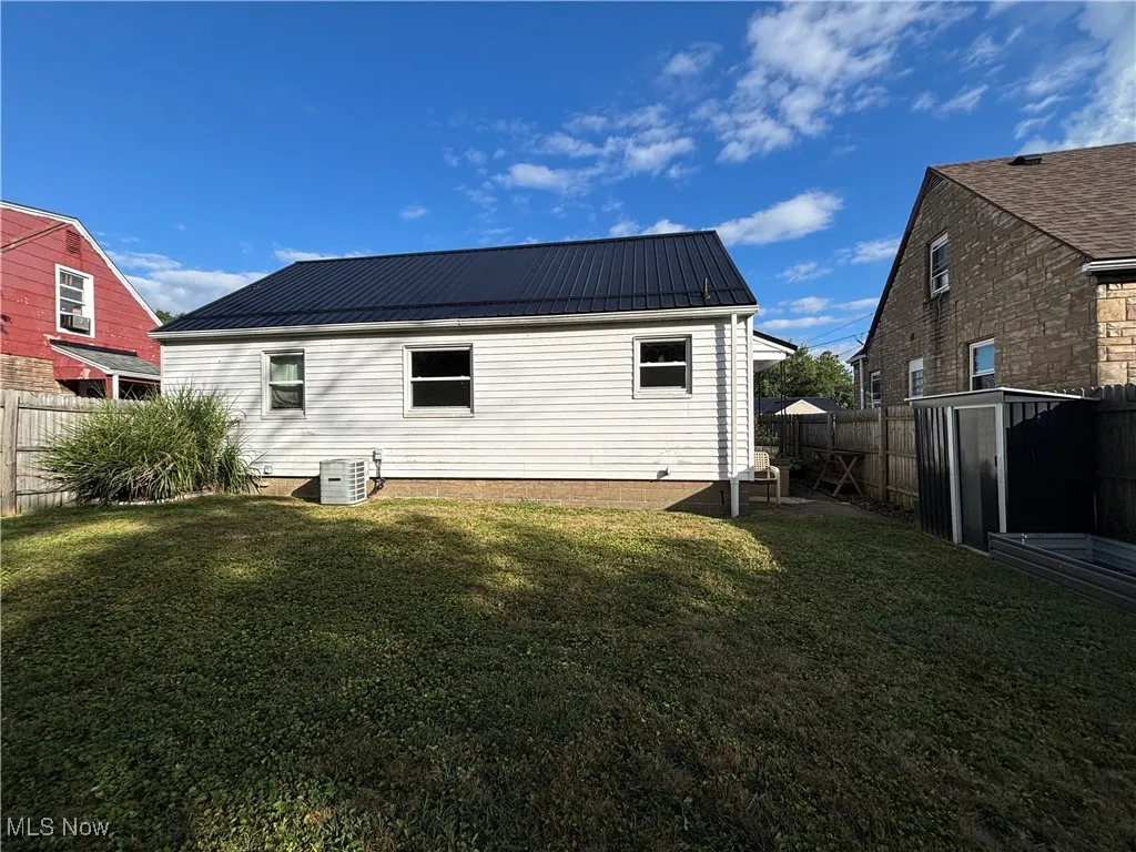 Back of house featuring a metal roof and a fenced backyard