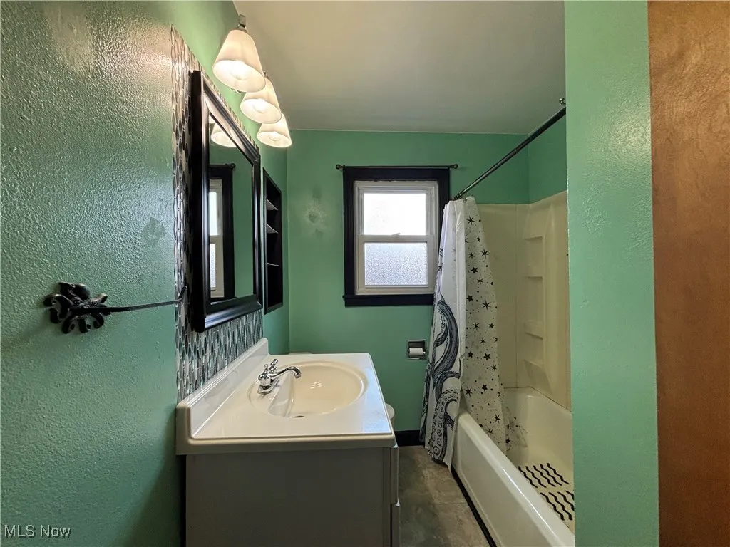 Full bathroom featuring a textured wall, shower / tub combo, and vanity