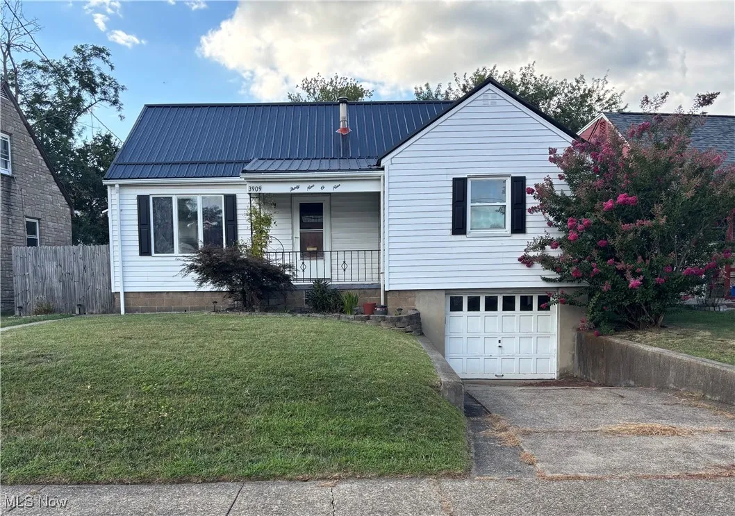 View of front facade featuring a metal roof, a garage, covered porch, and driveway