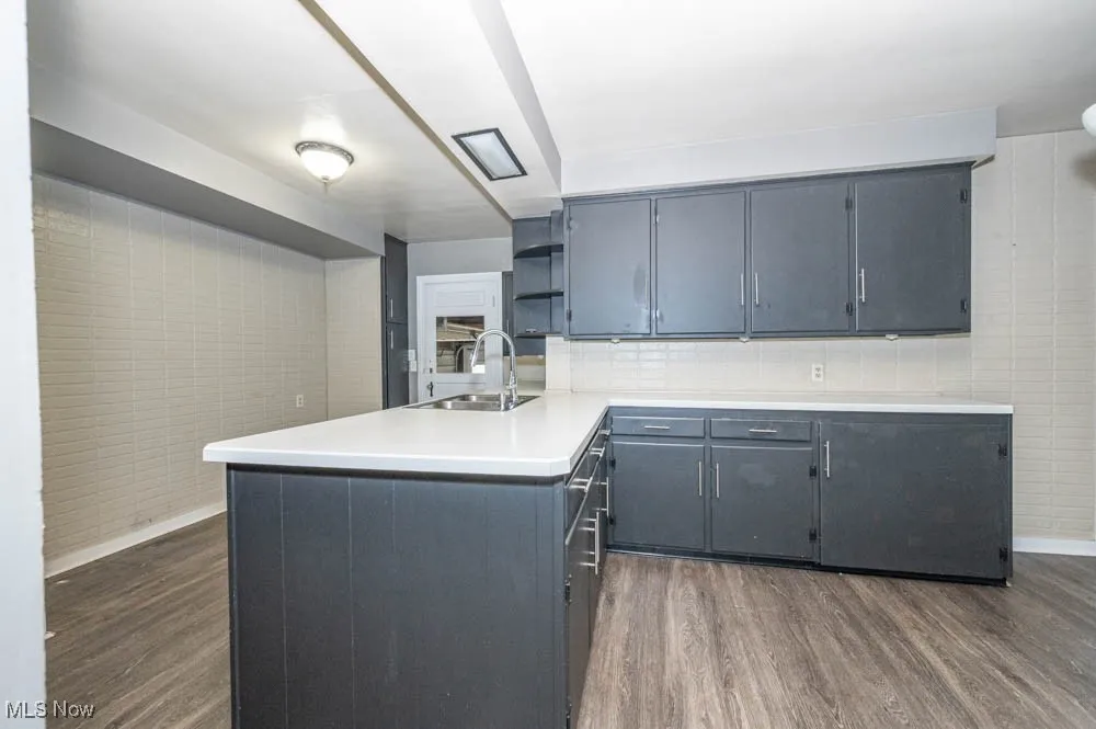 Kitchen featuring a peninsula, light countertops, plenty cabinetry, and wood-like finished flooring