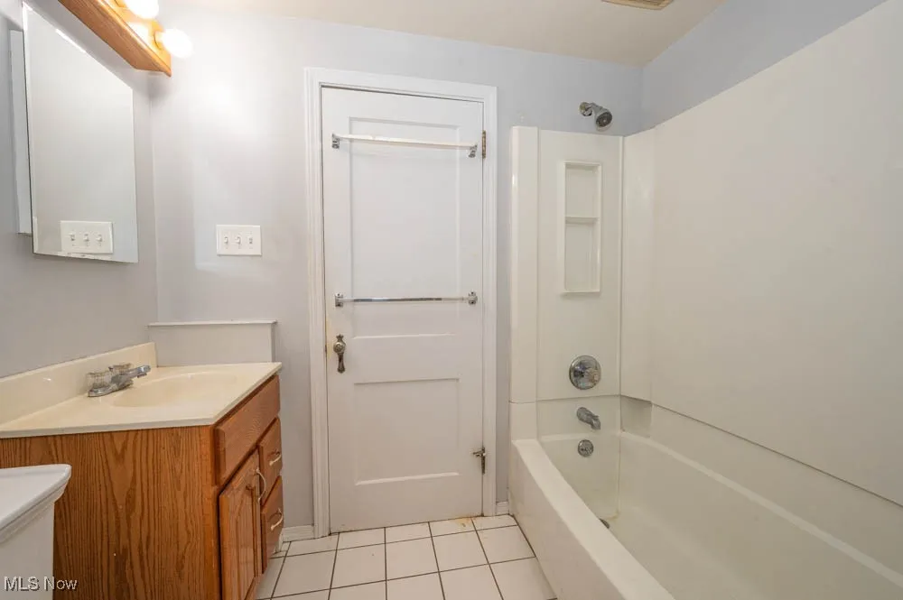 Bathroom featuring shower / bath combination, light tile patterned floors, and vanity