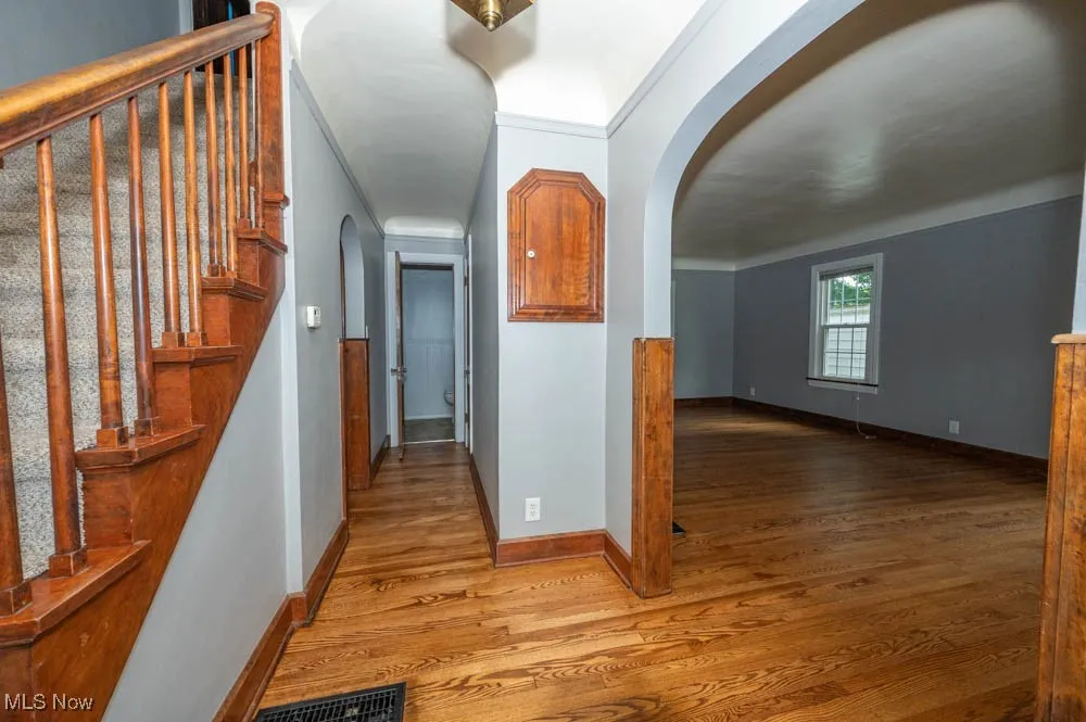 Entryway from front door with newly refinished hardwood floors and arched walkway into living room