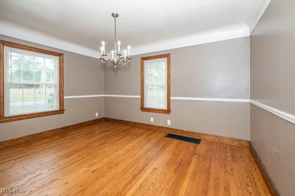 Living room with a chandelier, newly refinished hardwood floors, and decorative trim