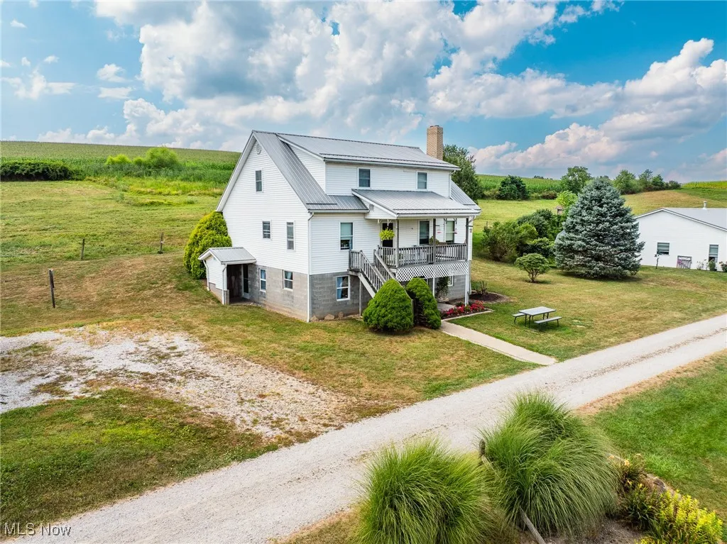 View of front of home with stairs, a chimney, a view of rural / pastoral area, a metal roof, and driveway
