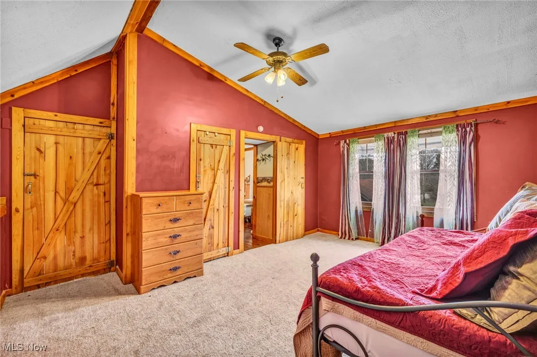 Carpeted bedroom featuring vaulted ceiling, baseboards, and ceiling fan