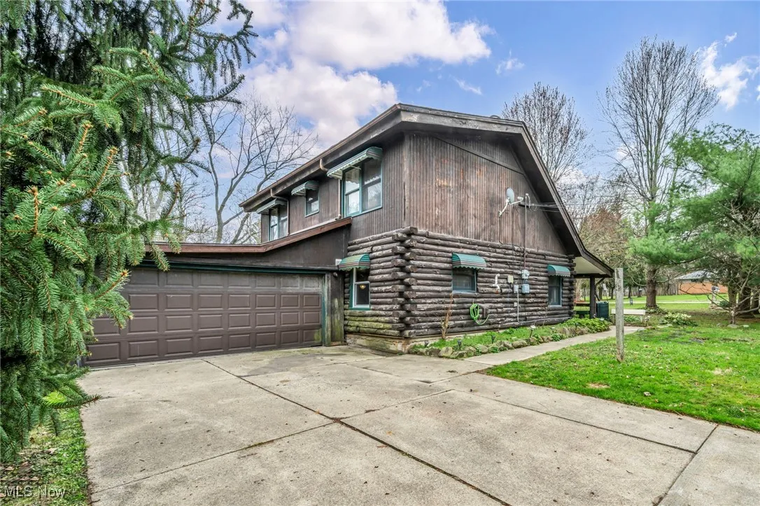 View of side of property with a lawn, driveway, and log siding