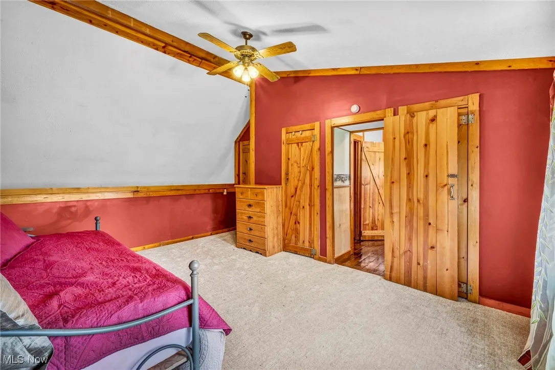 Carpeted bedroom featuring lofted ceiling, a ceiling fan, and visible vents