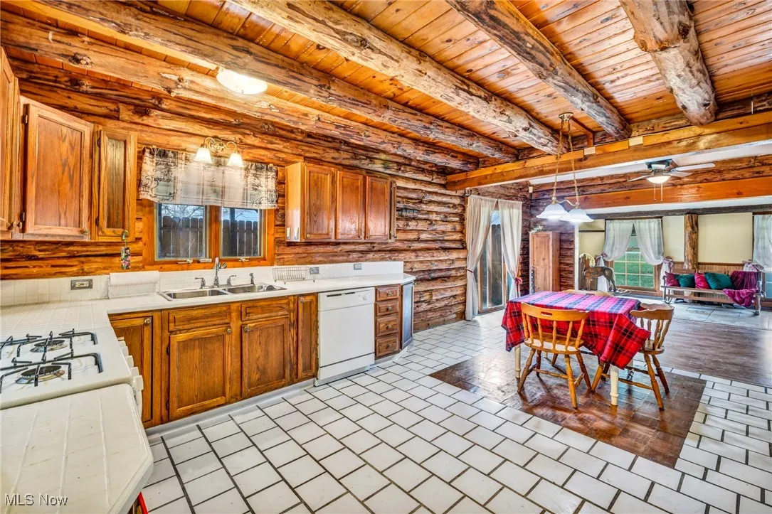 Kitchen featuring a sink, dishwasher, ceiling fan, light countertops, and wooden ceiling