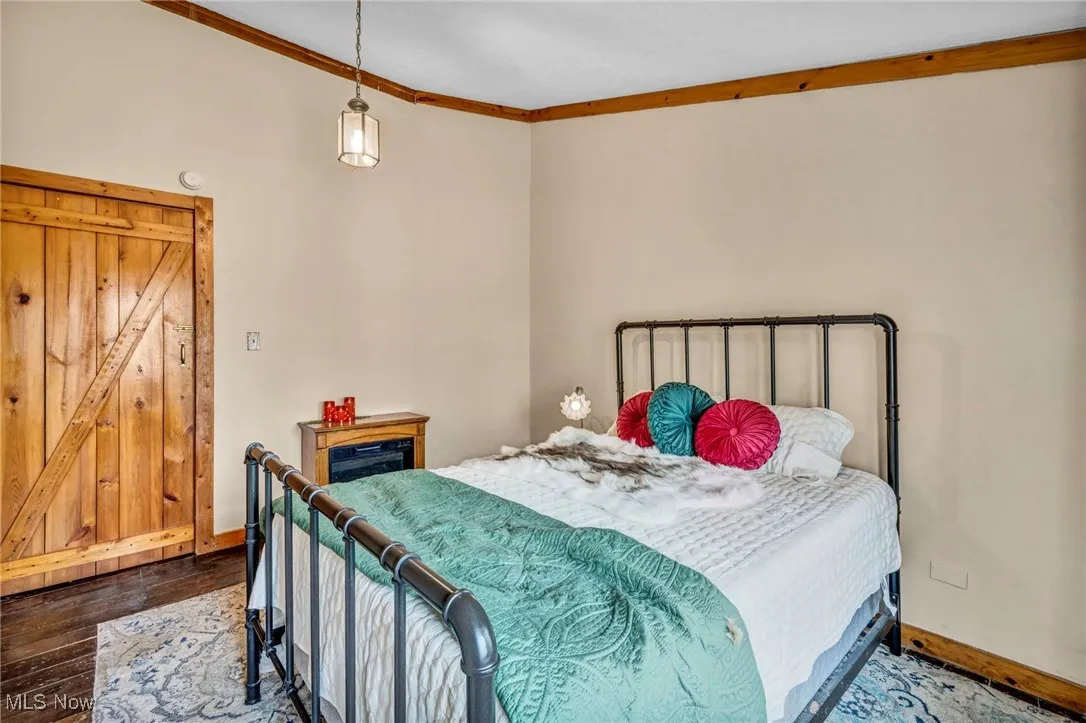 Bedroom with baseboards, wood finished floors, and crown molding