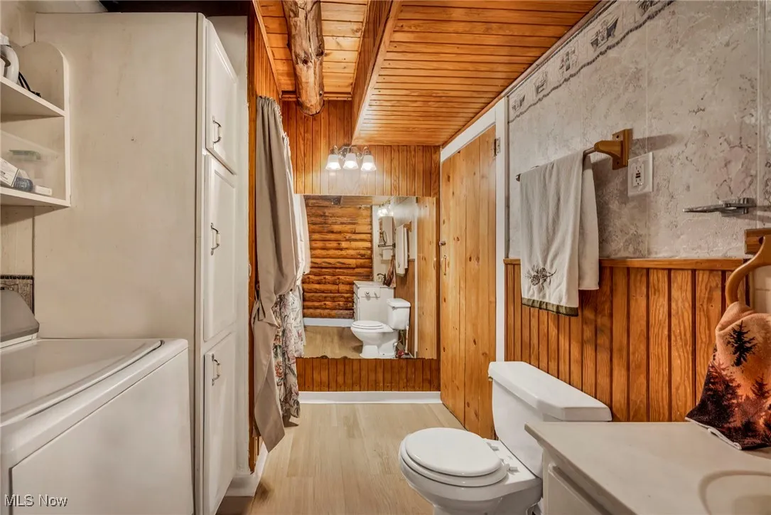 Full bathroom with wood finished floors, vanity, washer / dryer, wooden ceiling, and toilet