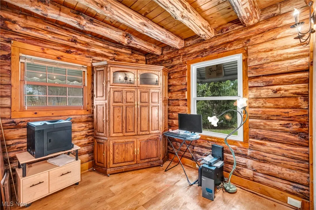 Home office with beamed ceiling, light wood-style flooring, log walls, and wooden ceiling