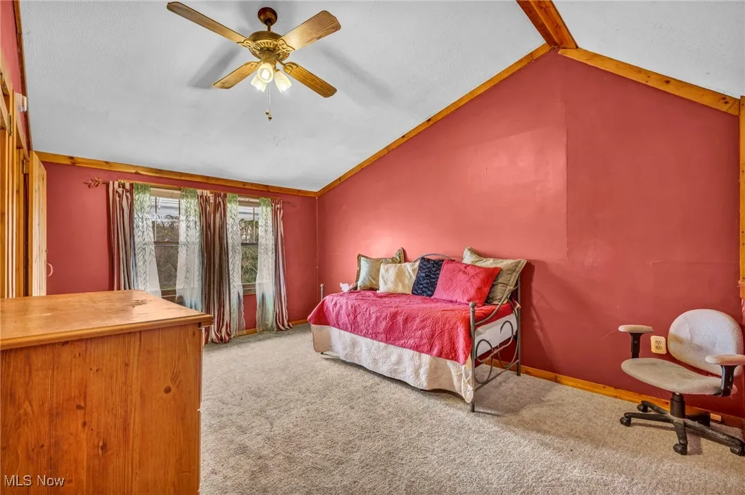 Carpeted bedroom featuring ceiling fan, lofted ceiling, and baseboards