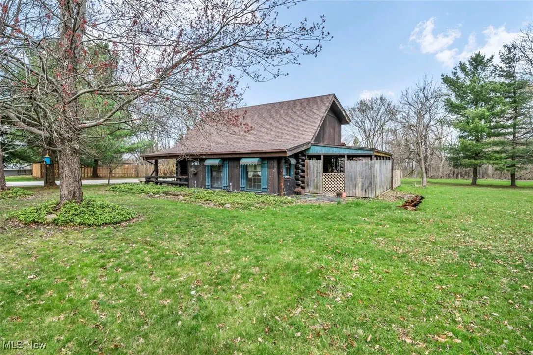 Rear view of house featuring a lawn and roof with shingles