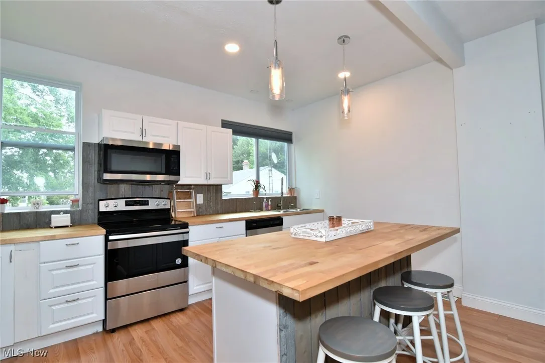 Kitchen featuring stainless steel appliances, wooden counters, light wood-type flooring, recessed lighting, and beam ceiling