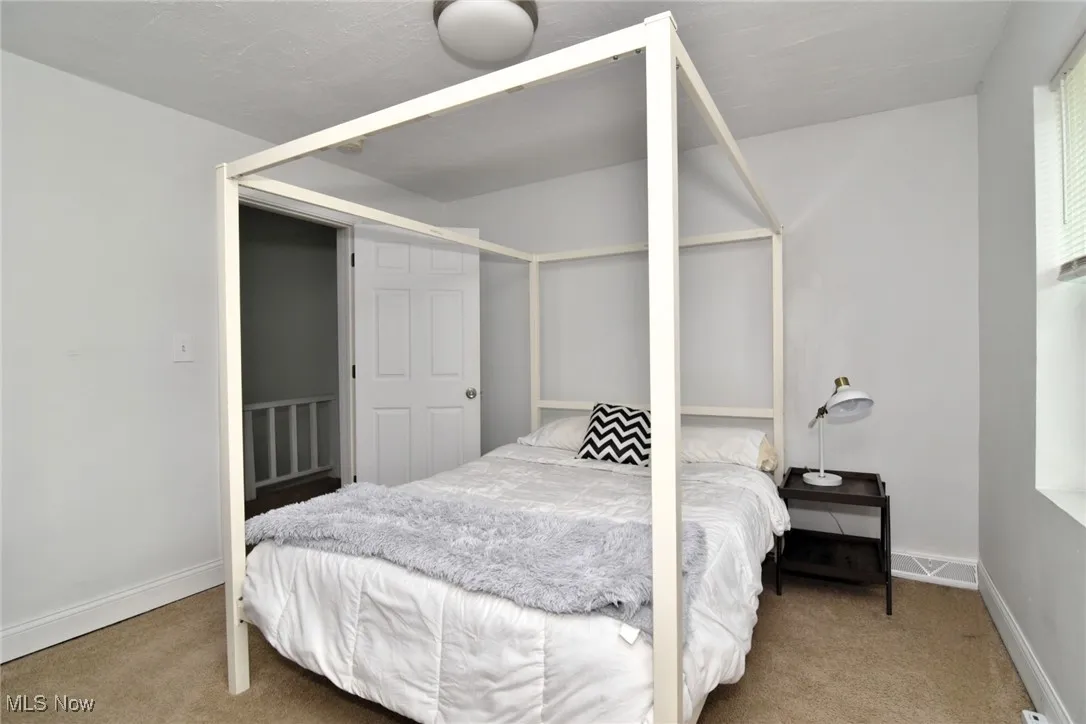 Bedroom with baseboards and light colored carpet