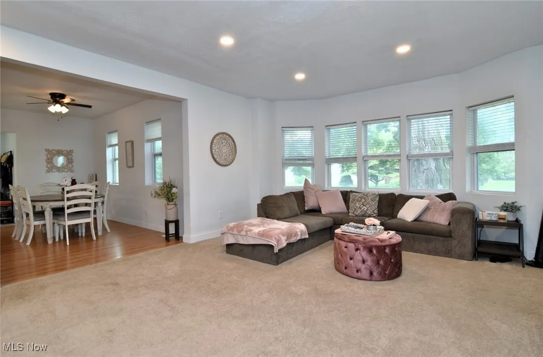 Living room with light colored carpet, recessed lighting, light wood-style flooring, and ceiling fan